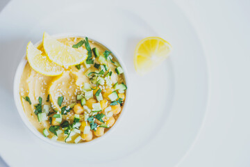 Hummus from chickpeas, with olive oil, lemon, sesame seeds and cucumbers, on white background.