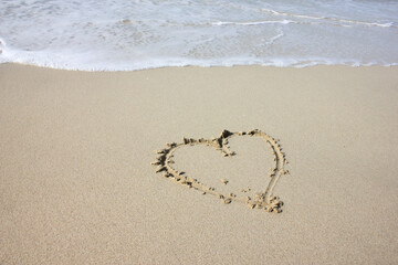 a heart is drawn on the sand of the beach