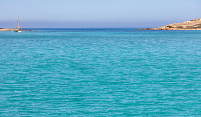 Cyclades islands, Rinia bay clear transparent water, Greece. Turquoise blue sea, island coast and blue sky background.