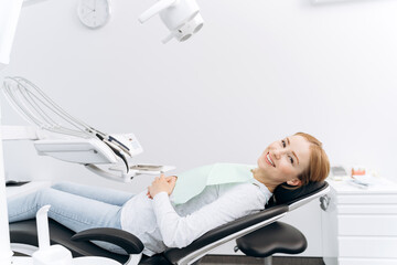 Patient is lying in a dental chair, waiting for the dentist. Attractive woman in the dental office