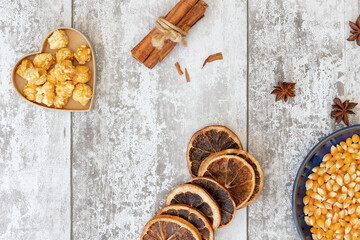 Popcorn cinnamon sticks, orange slices a star anise shot from above on white wooden background, National Popcorn Day