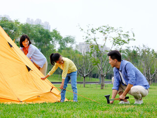 A happy family of three set up tents outdoors