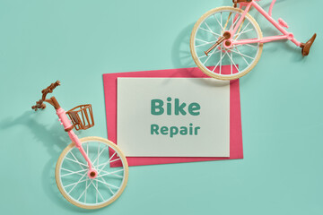 Bike repair workshop. Bicycle Repair flat lay with broken toy model town bike. Top view on mint...