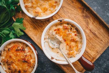 Julienne in portions, Mushrooms with cream and cheese casserole, Restaurant food on a dark background, Top view