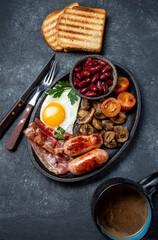 English Breakfast with fried eggs, sausages, bacon, beans, toasts, tomatoes and mushrooms