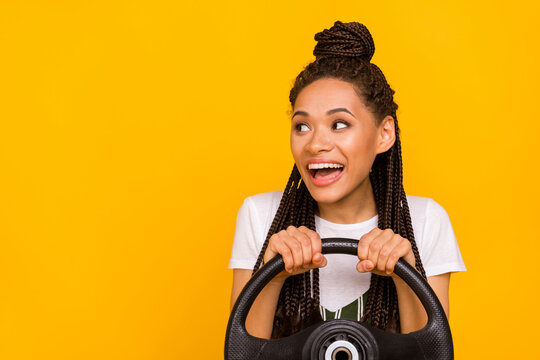 Photo of amazed happy afro american young woman look empty space drive car smile isolated on yellow color background