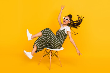 Full length photo of cute charming dark skin lady wear striped clothes sitting chair smiling isolated yellow color background