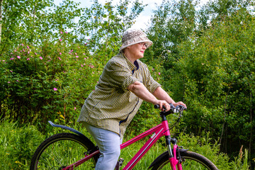 Fototapeta na wymiar Grandma rides a bike. An elderly woman rides a bicycle in nature.
