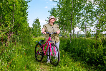 Fototapeta na wymiar Grandma rides a bike. An elderly woman rides a bicycle in nature.