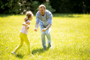 Father chasing his little daughter while playing in the park