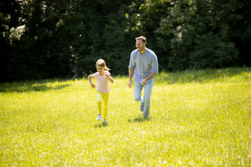 Fototapeta premium Father chasing his little daughter while playing in the park