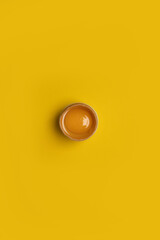 Minimal Easter concept idea. Fresh Easter one brown chicken broken egg with yolk on yellow background.