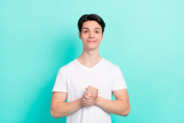 Photo of funny brunet hairdo teen guy hold hands wear white t-shirt isolated on vibrant teal color...