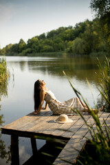 Relaxing young woman on wooden pier at the lake