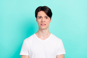 Photo of dislike brunet hairdo teen guy wear white t-shirt isolated on bright teal color background