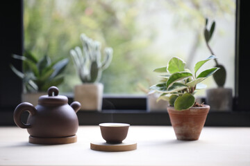 Tea cup with clay teapot and Hoya Carnosa plant on wooden table