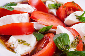 Caprese salad with pesto sauce on a white plate