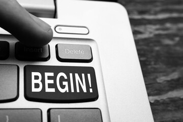 BEGIN word concept on the keyboard. Finger hits the delete or BEGIN button on the laptop keyboard, close up.