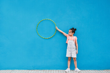 Cute little girl holding hula hoop ring - Child having playful time in the city - obrazy, fototapety, plakaty