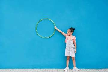 Foto op Plexiglas Cute little girl holding hula hoop ring - Child having playful time in the city © Sabrina
