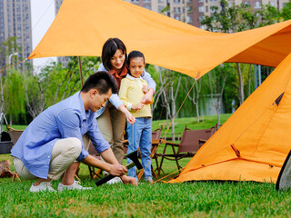 A happy family of three set up tents outdoors