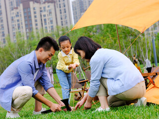 A happy family of three set up tents outdoors