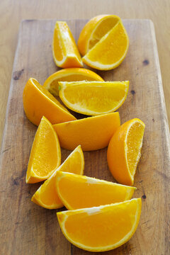 yellow oranges sliced in wedges on a wooden board