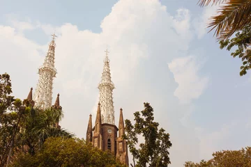 Fotobehang The majestic towers of the Catholic cathedral in Jakarta with retro style toning. Divine temple of christianity under beautiful blue sky in daylight. SUblime construction for believers. God's home. © Ольга Ким