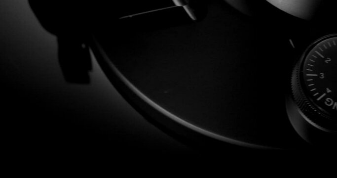 Extreme closeup of counterweight and anti-skating control dial on black vinyl turntable, panoramic view