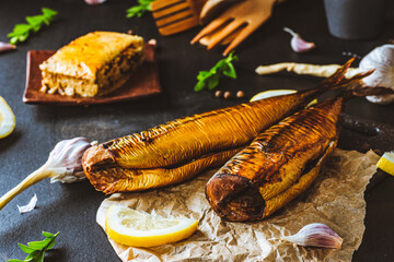 Mackerel. Smoked mackerel with additions. Fish with spices. Smoked food on a dark background. - obrazy, fototapety, plakaty