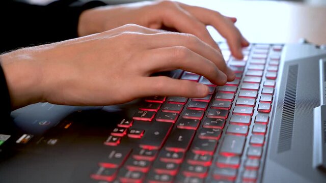 Women's beautiful hands typing on a laptop keyboard close-up. Blurred background.