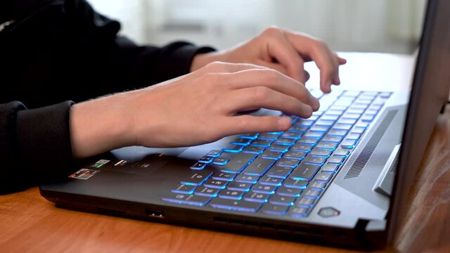 Women's beautiful hands typing on a laptop keyboard close-up. Blurred background.