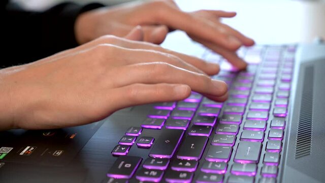 Women's beautiful hands typing on a laptop keyboard close-up. Blurred background.