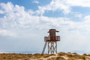 Landscape of isolated lifeguard post , Tarifa beach. Sand dunes and typically environment for south of Spain. Blue sky with clouds and the lifeguard post made by wood. No people  