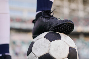 Legs of a female soccer or football player on ball at stadium, close up