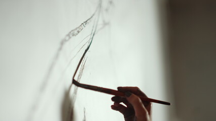Woman hand making brush stroke on picture. Female painter working indoors.