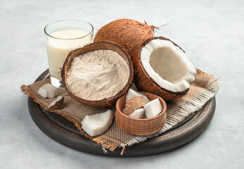 Coconut flour, coconut milk and fresh opened coconut on a gray background.