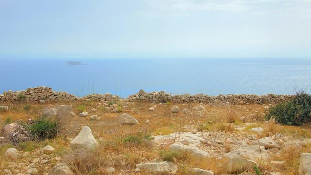 A landscape of the Maltese coast with the ruins of an ancient wall. Filfla island.