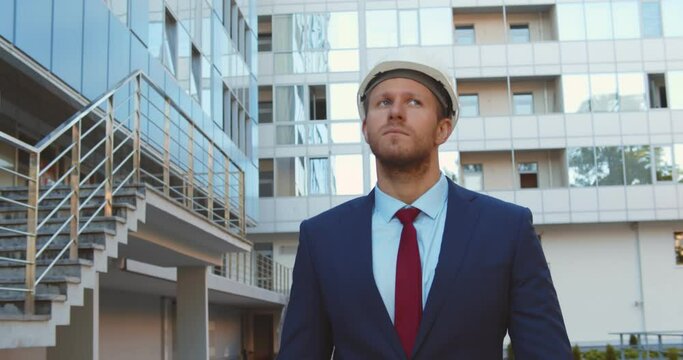 Confident construction manager wearing hardhat walking outside modern building