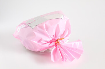 Pink Plastic gift bag with ribbon on white.