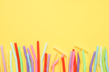 top view of colorful plastic straws on yellow background, flat lay, copy space.