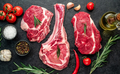 Assorted raw beef steaks. Tomahawk steak and ribeye steaks on stone background