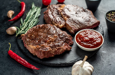 Two grilled ribeye steaks on stone background