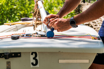 Sailboat repair and  maintenance: close up of tools , shackels and hands in use to refit the boom on a a small dingy's .