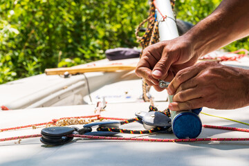 Sailboat repair and  maintenance: close up of tools , shackels and hands in use to refit the boom...