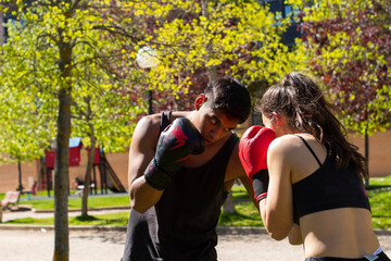Close-up - a strong young beautiful woman professional athlete practicing strikes with her man coach during a street workout. Concept of women in men's sports