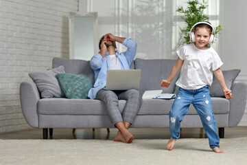 kid dancing and busy dad working with laptop at home - obrazy, fototapety, plakaty