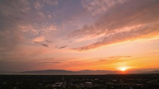 Moving timelapse at sunset overlooking Utah Valley past Orem City as colorful clouds move through the sky.