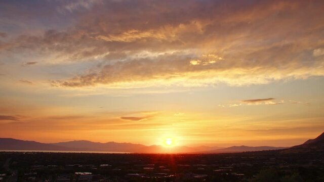 Timelapse of the sun setting over Utah Valley looking over Orem as it fades behind the mountains.