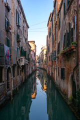 Venetian old Residential Waterfront Houses in green narrow Canal of Venice, Italy